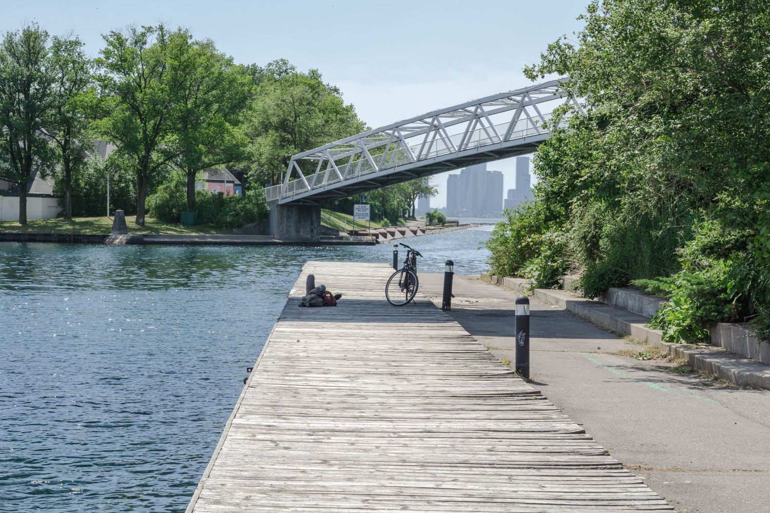 Wooden boardwalk along waterfront with bridge visible in the background.