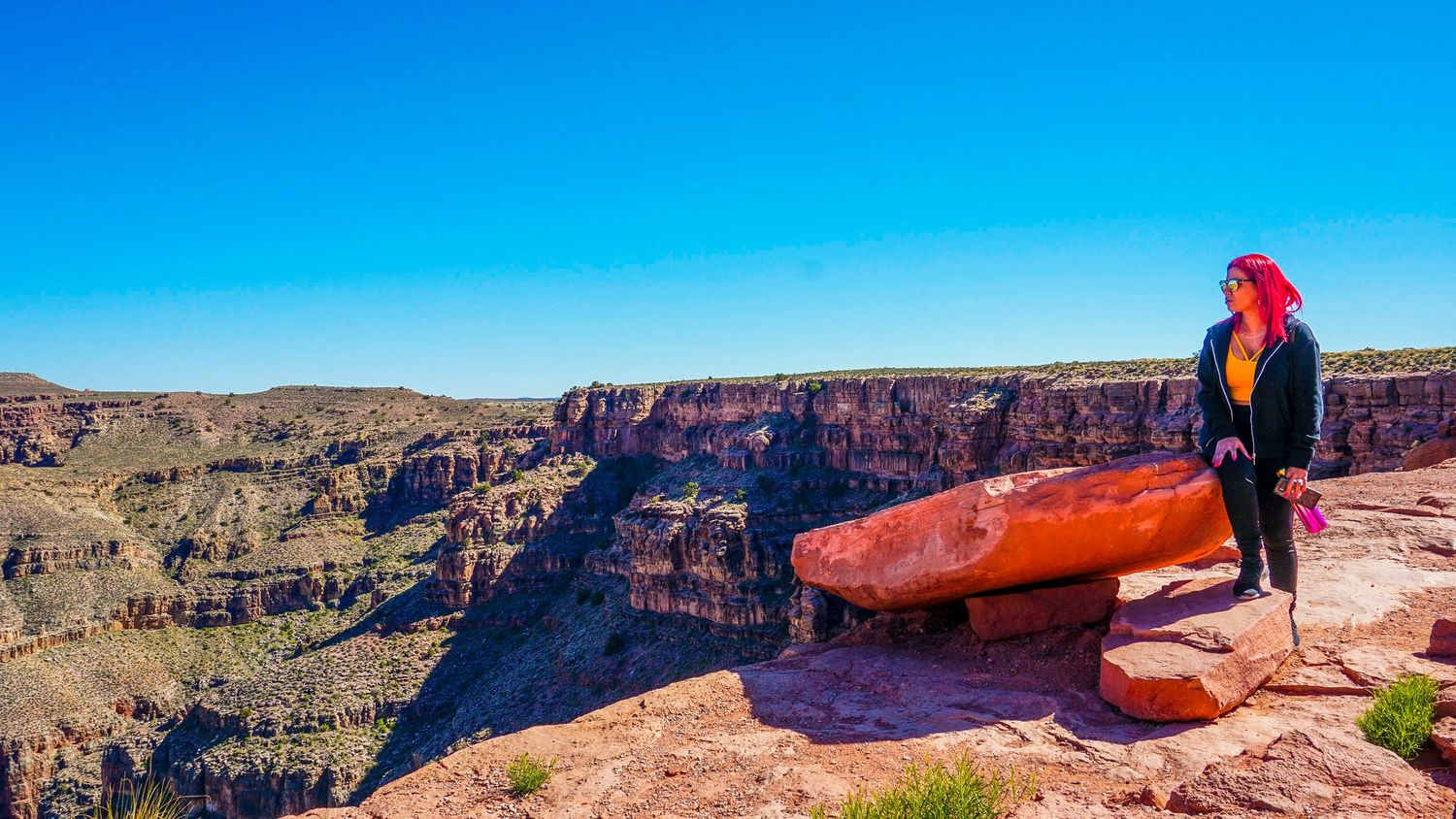 Panoramic view of red rock formations at the Grand Canyon under bright blue skies.