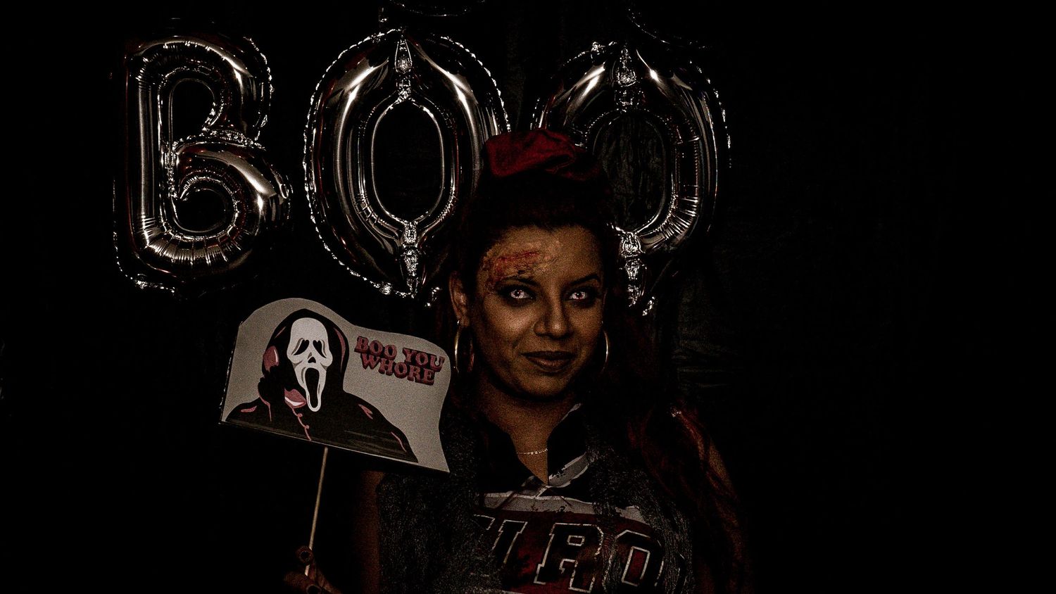 Dark party setting with silver balloon decorations visible in the background.