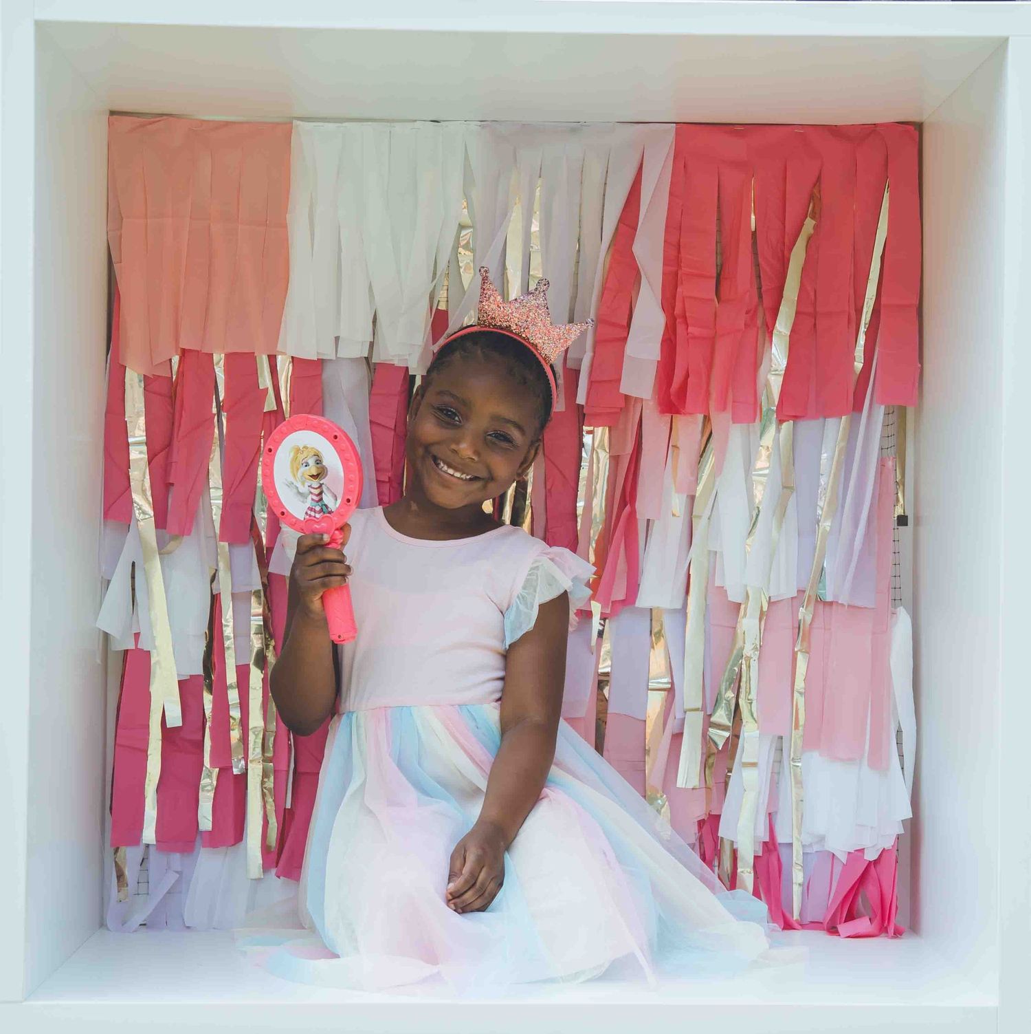 People posing together in a decorated white studio space with pink hanging streamers.
