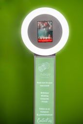Row of digital display kiosks with green illuminated screens mounted on a wall.