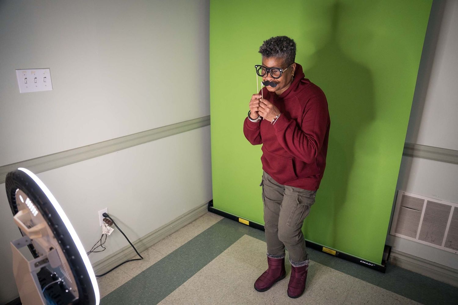Photography session taking place in studio space with green wall backdrop.