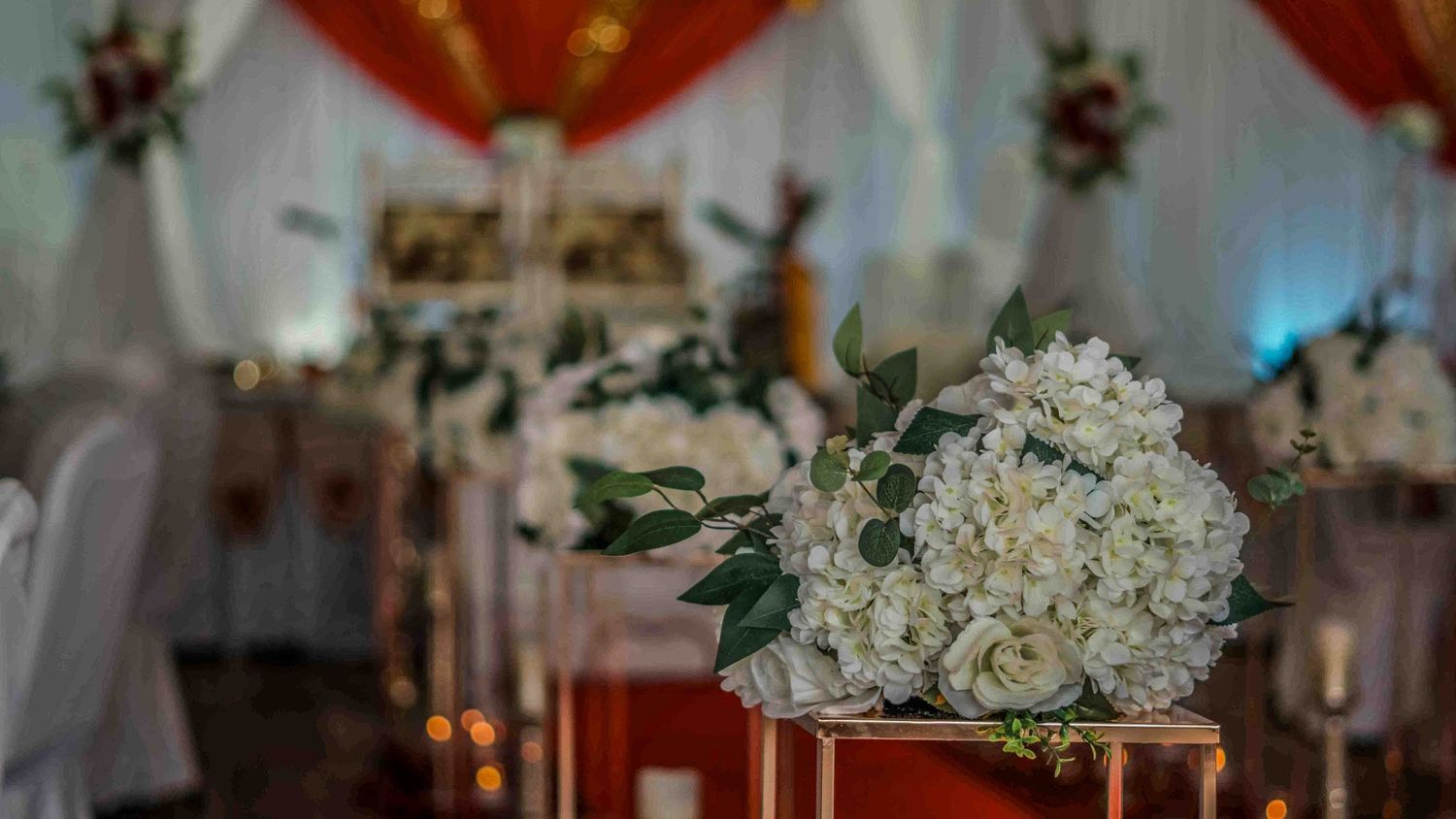 Close-up of red and white flower arrangements with decorative lighting elements.