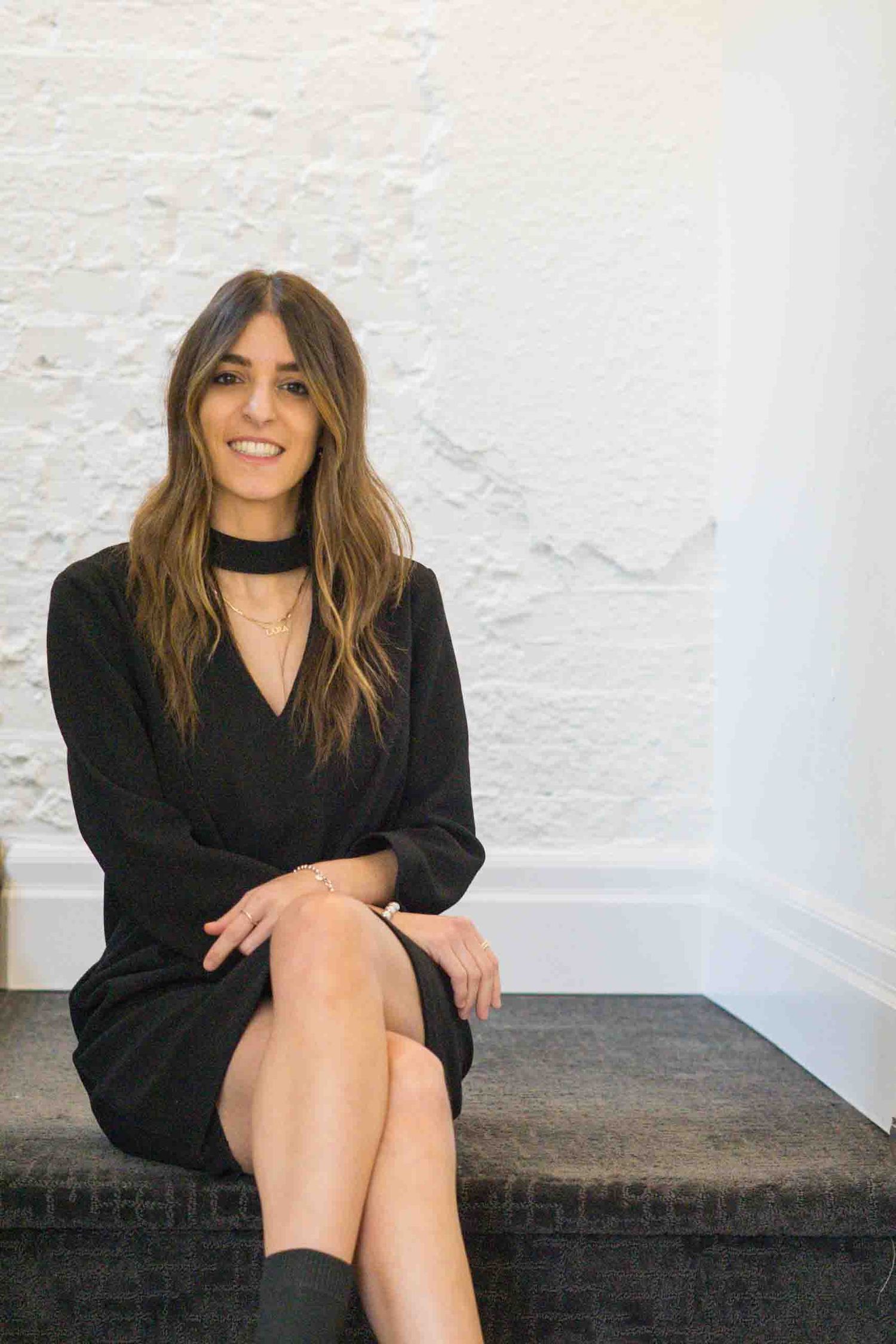 Lifestyle portraits on dark bench against white wall showing relaxed poses in black outfit.