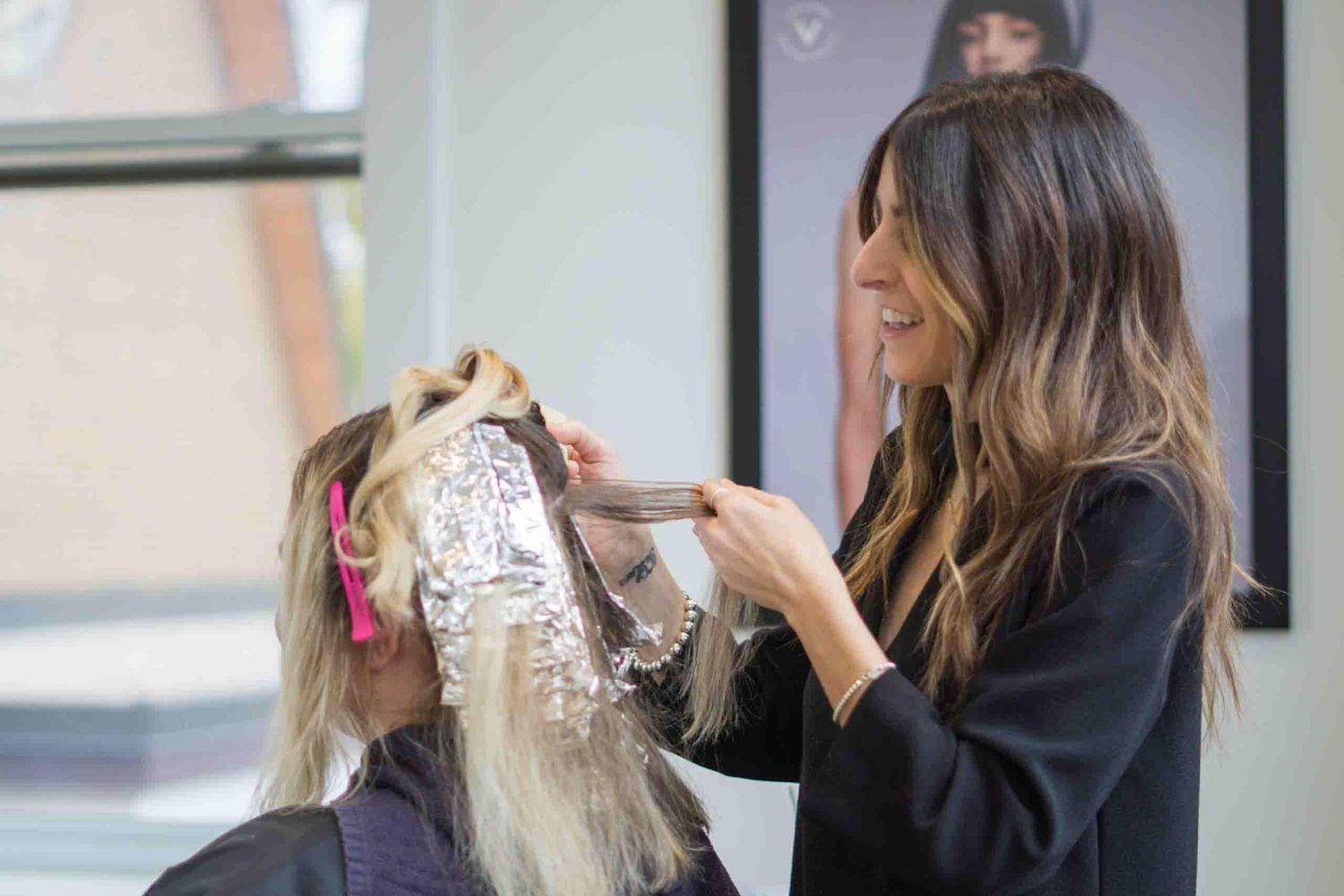 A hair coloring session shows foils being applied in a professional salon environment.