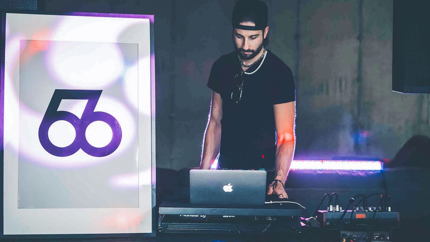 DJ performing at nightclub with illuminated number 56 logo display.
