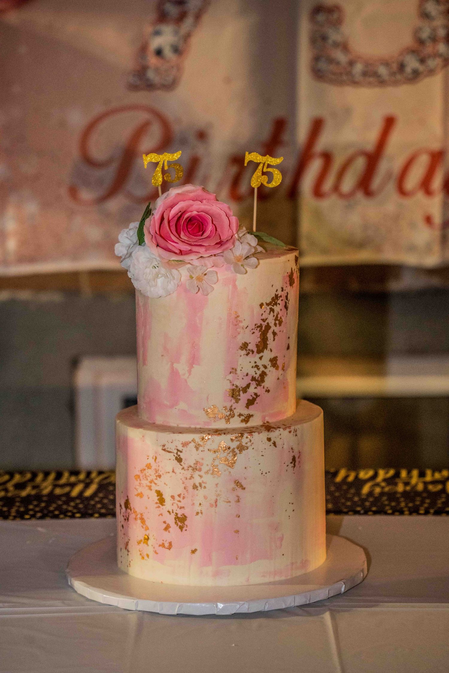 An elegant pink wedding cake with gold accents and floral decorations displayed on a table.