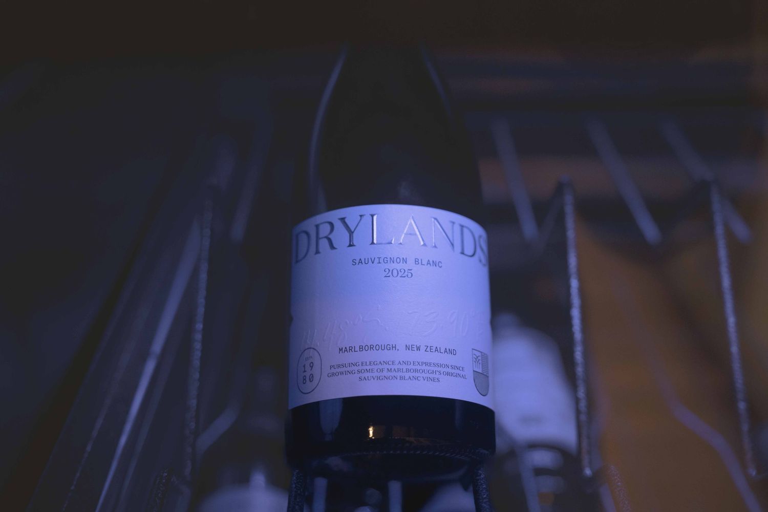 Drylands Sauvignon Blanc wine bottle on display in a dimly lit wine rack in Marlborough, New Zealand.