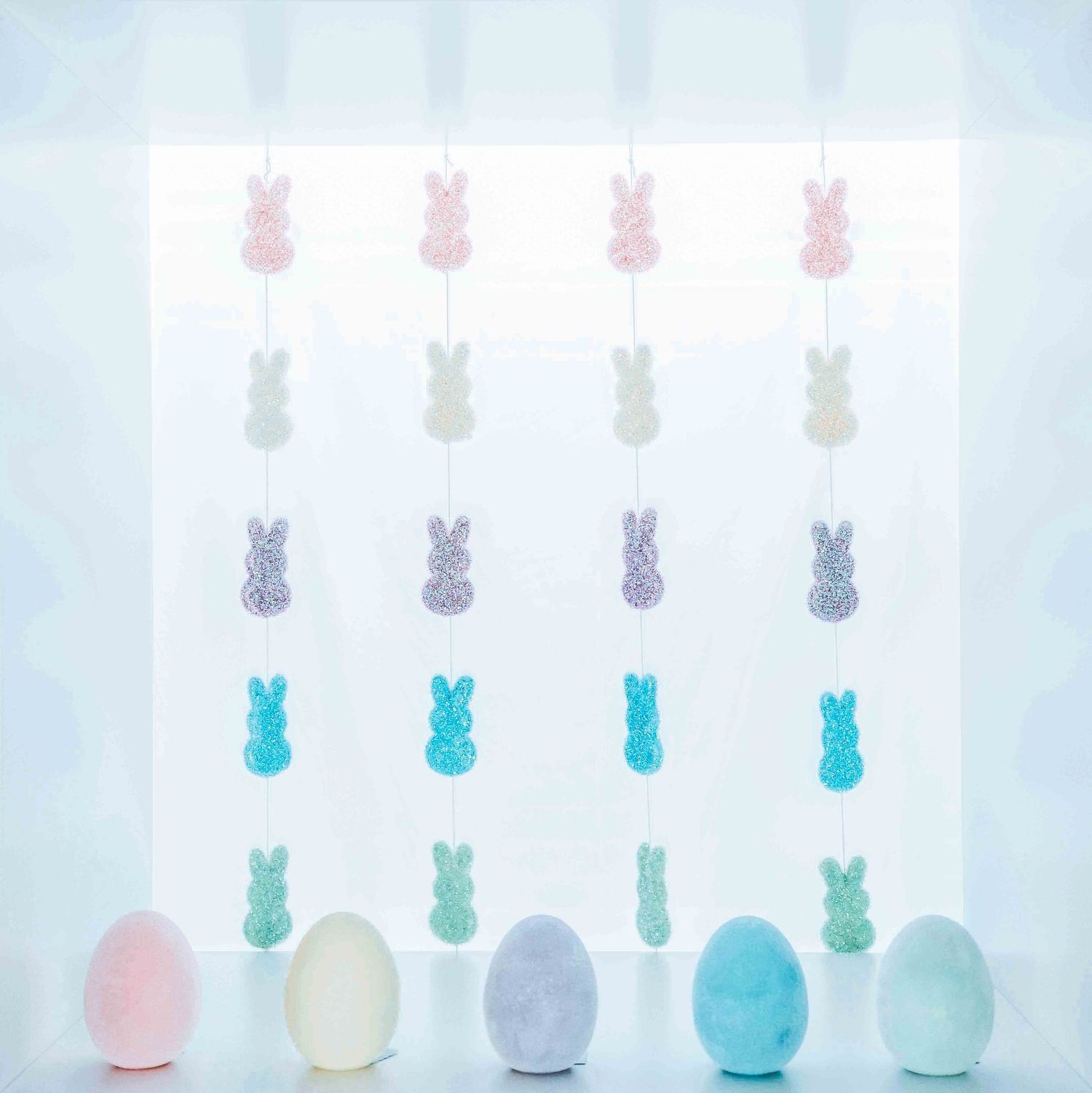 Pastel Easter eggs and bunny decorations arranged in neat rows against white background.