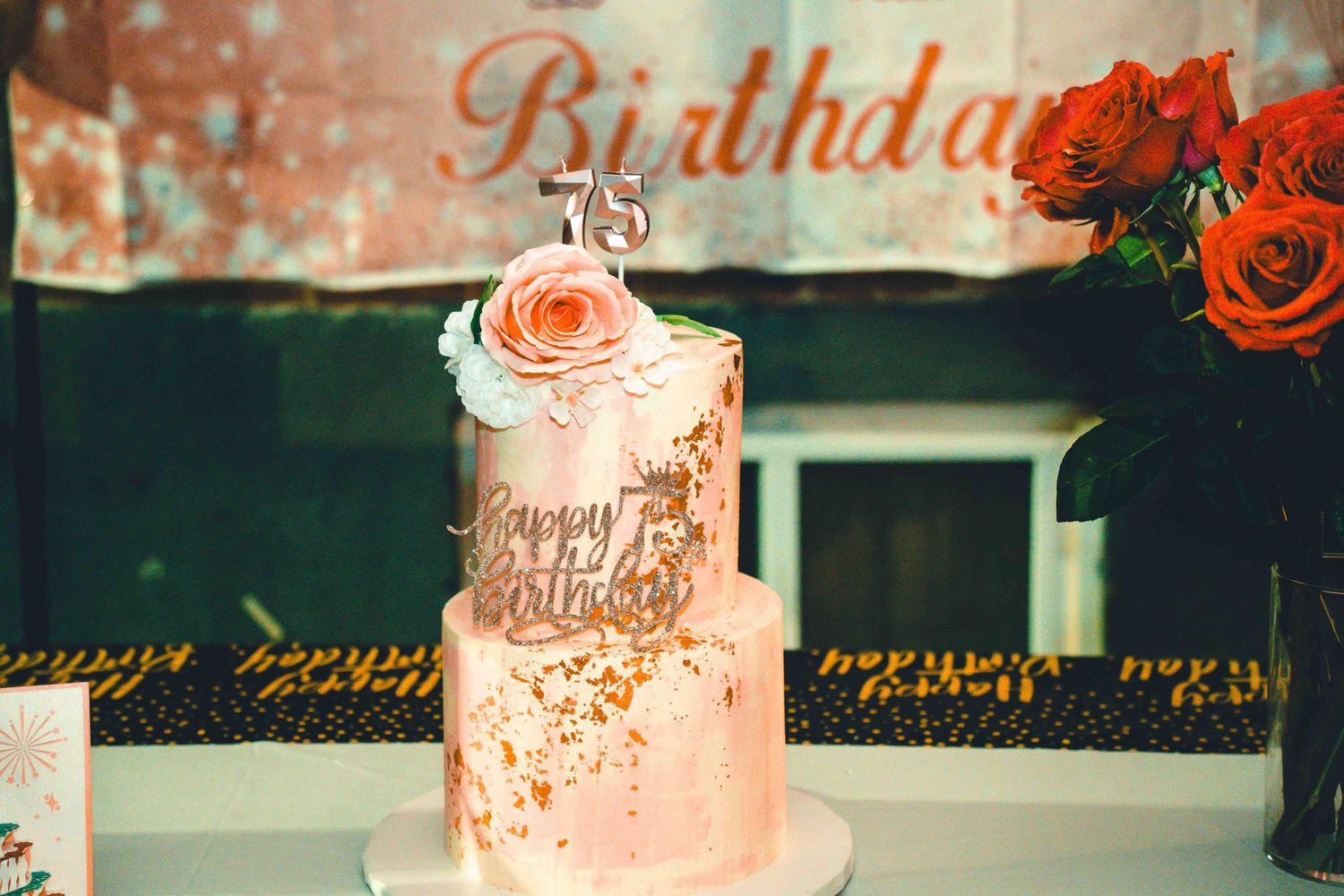 Elegant birthday cake with rose gold details and fresh floral decorations.