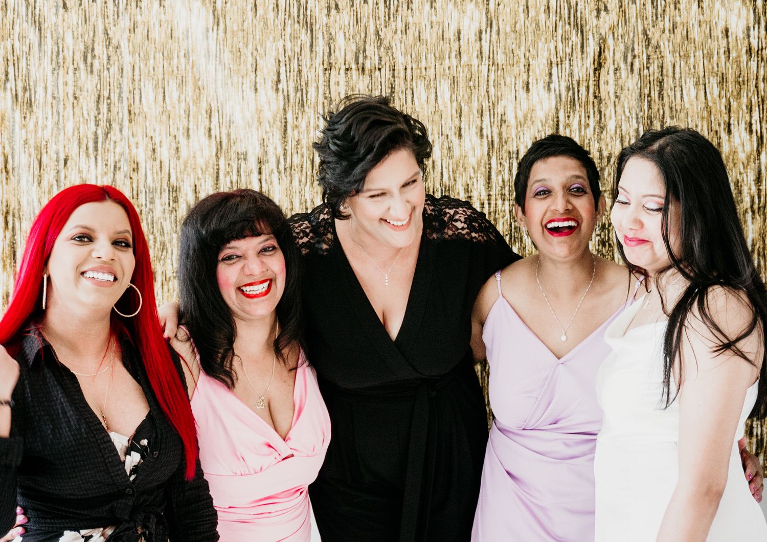 Group photo against a gold metallic backdrop at a formal event.