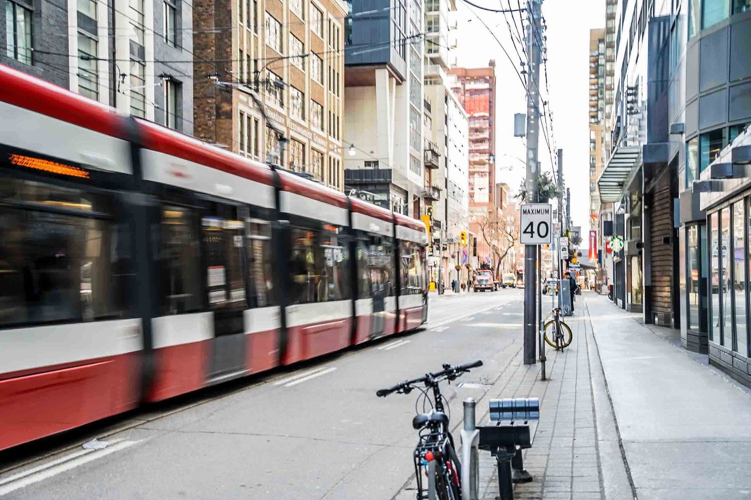 Urban street scene with TTC streetcars and buildings along a downtown Toronto thoroughfare.