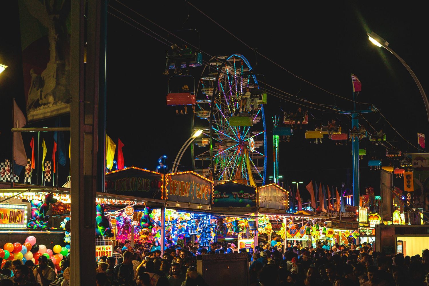 Carnival midway at night with bright lights and rides creating a festive atmosphere.