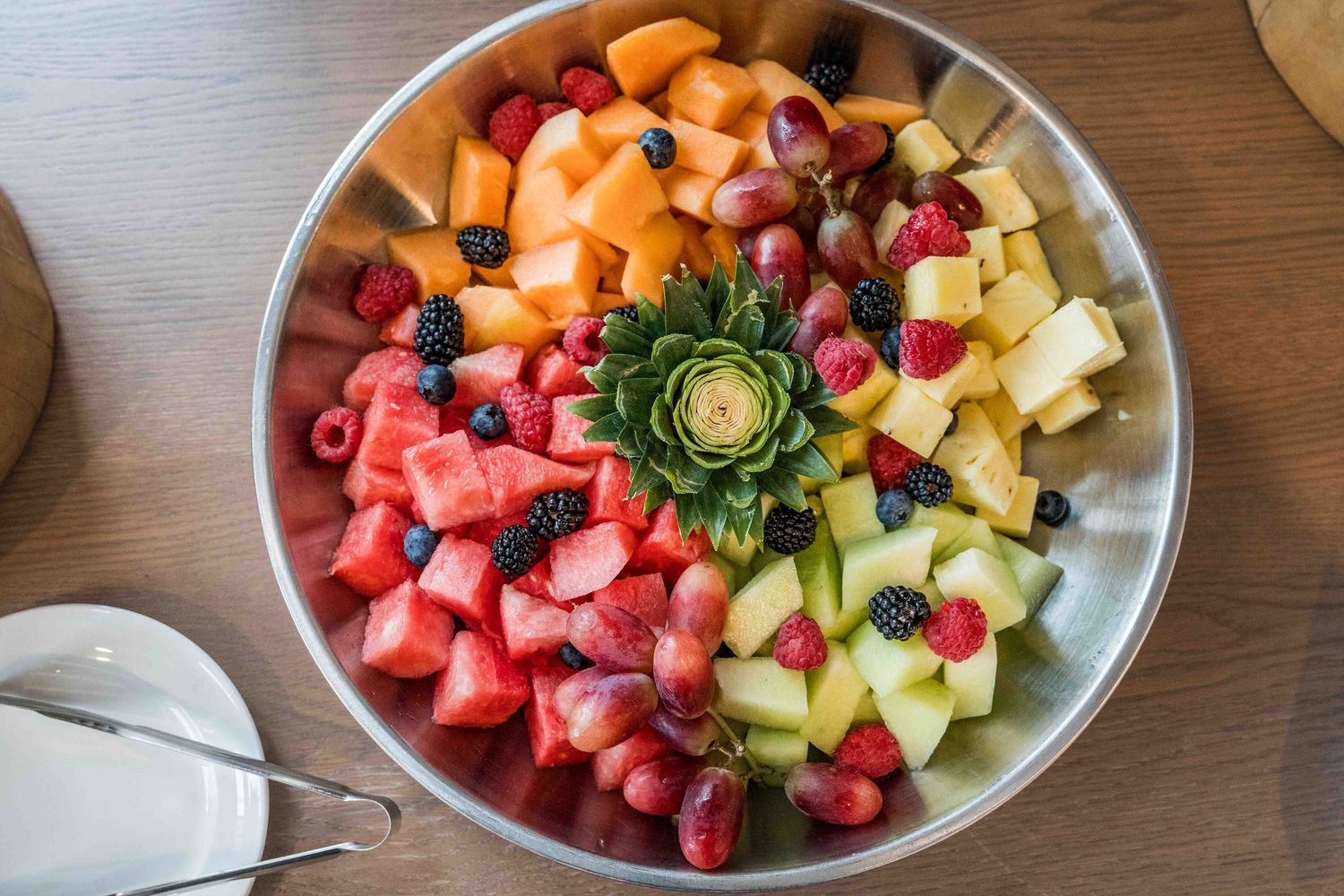 Colorful fresh fruit platter with watermelon, cantaloupe, honeydew, strawberries, and berries in a bowl.