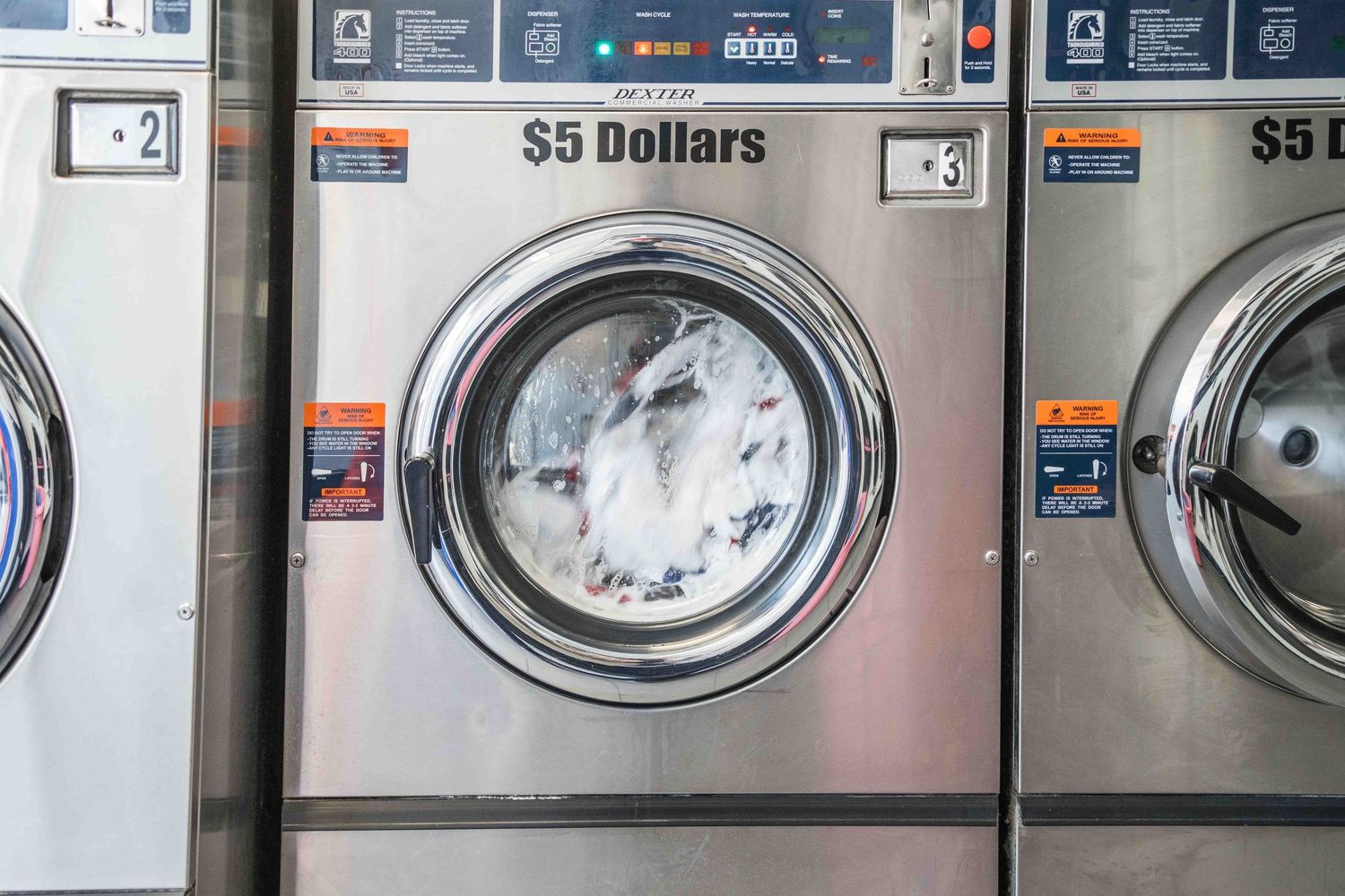 Stainless steel commercial laundry washing machine at a laundromat with a $5 dollar cycle cost.