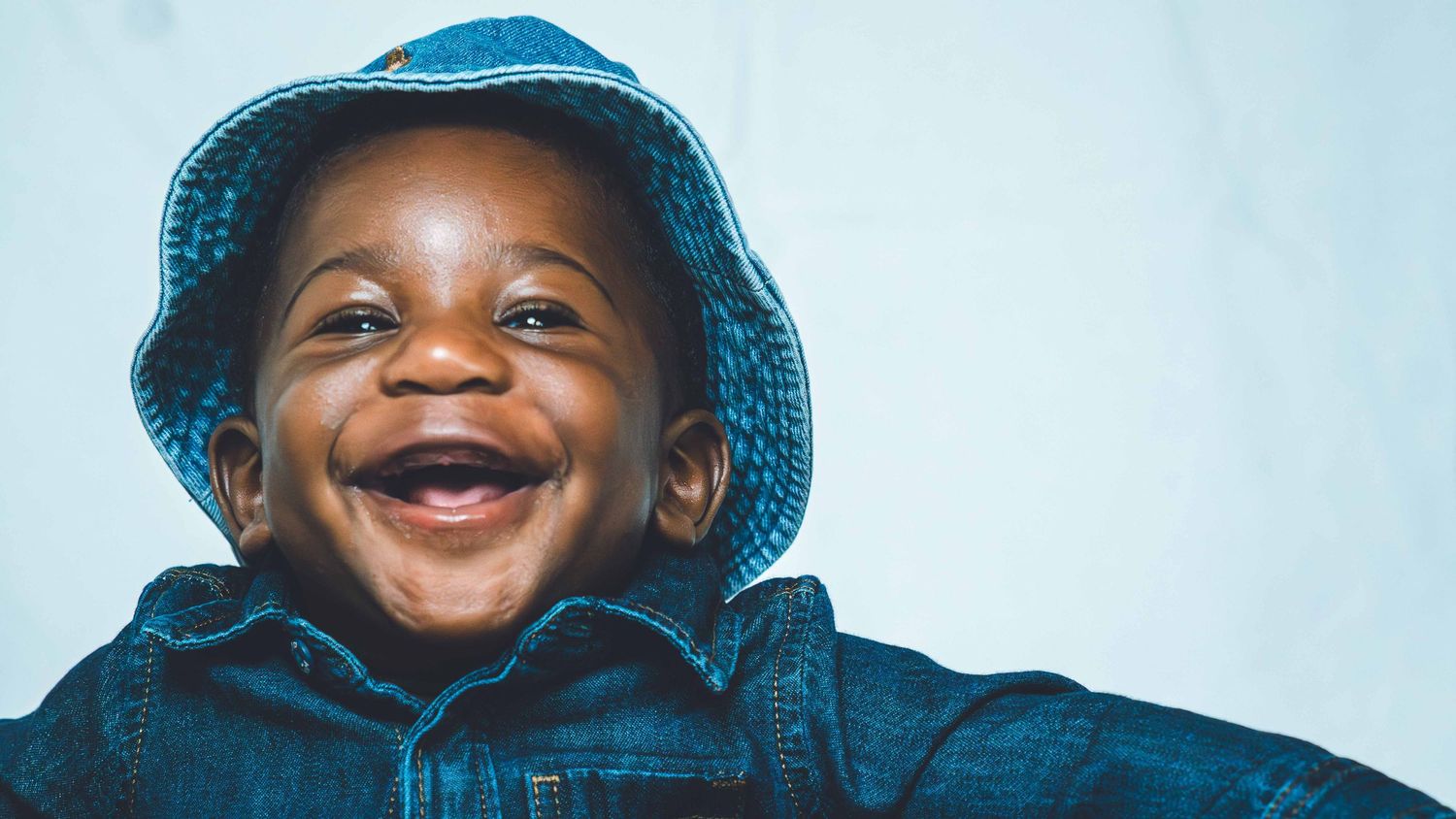 Close-up series of joyful expressions from child wearing blue denim.