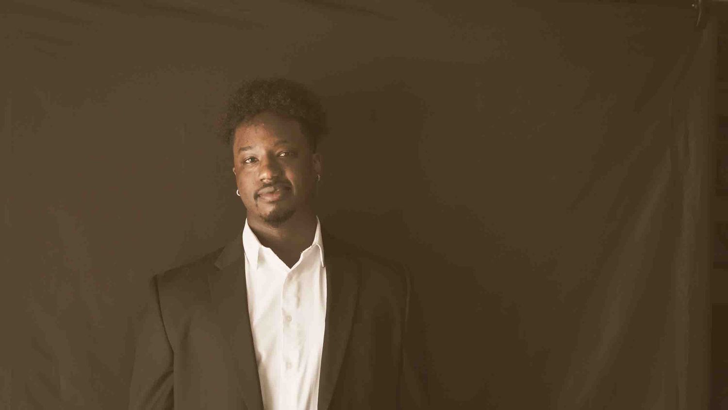 Professional studio portrait against dark background in formal attire.
