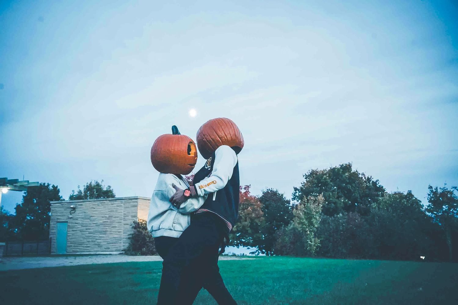 A basketball player practices shooting drills on an outdoor court at dusk.