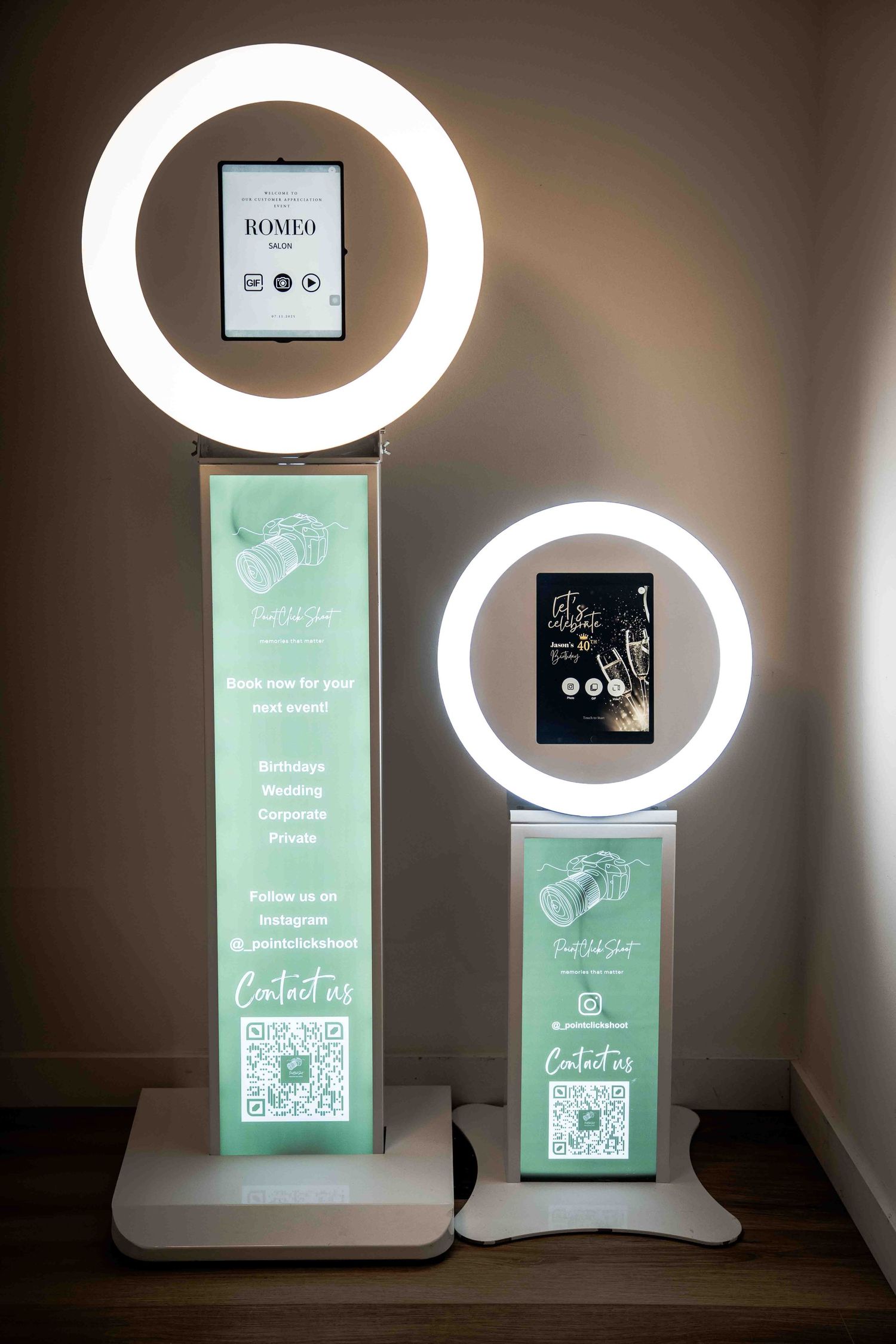 White photo booth kiosk with dual ring lights and digital display screens showing service options.