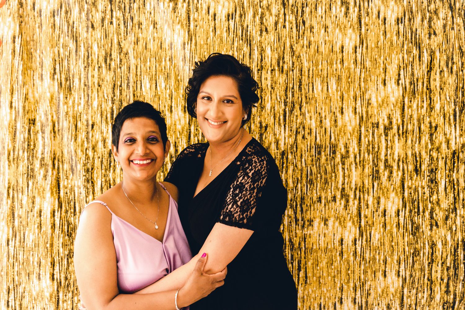 Celebratory gathering with people posed against a shimmering gold backdrop.