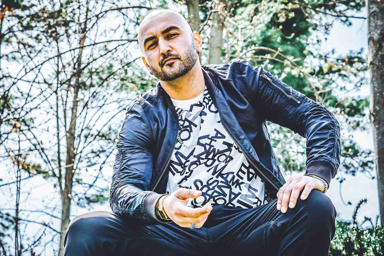Casual portrait of person in leather jacket sitting outdoors.
