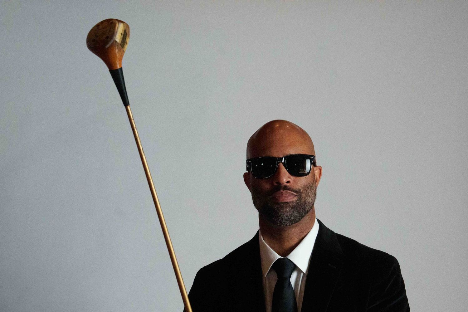 Person in black suit and sunglasses shown in multiple angles against gray background.