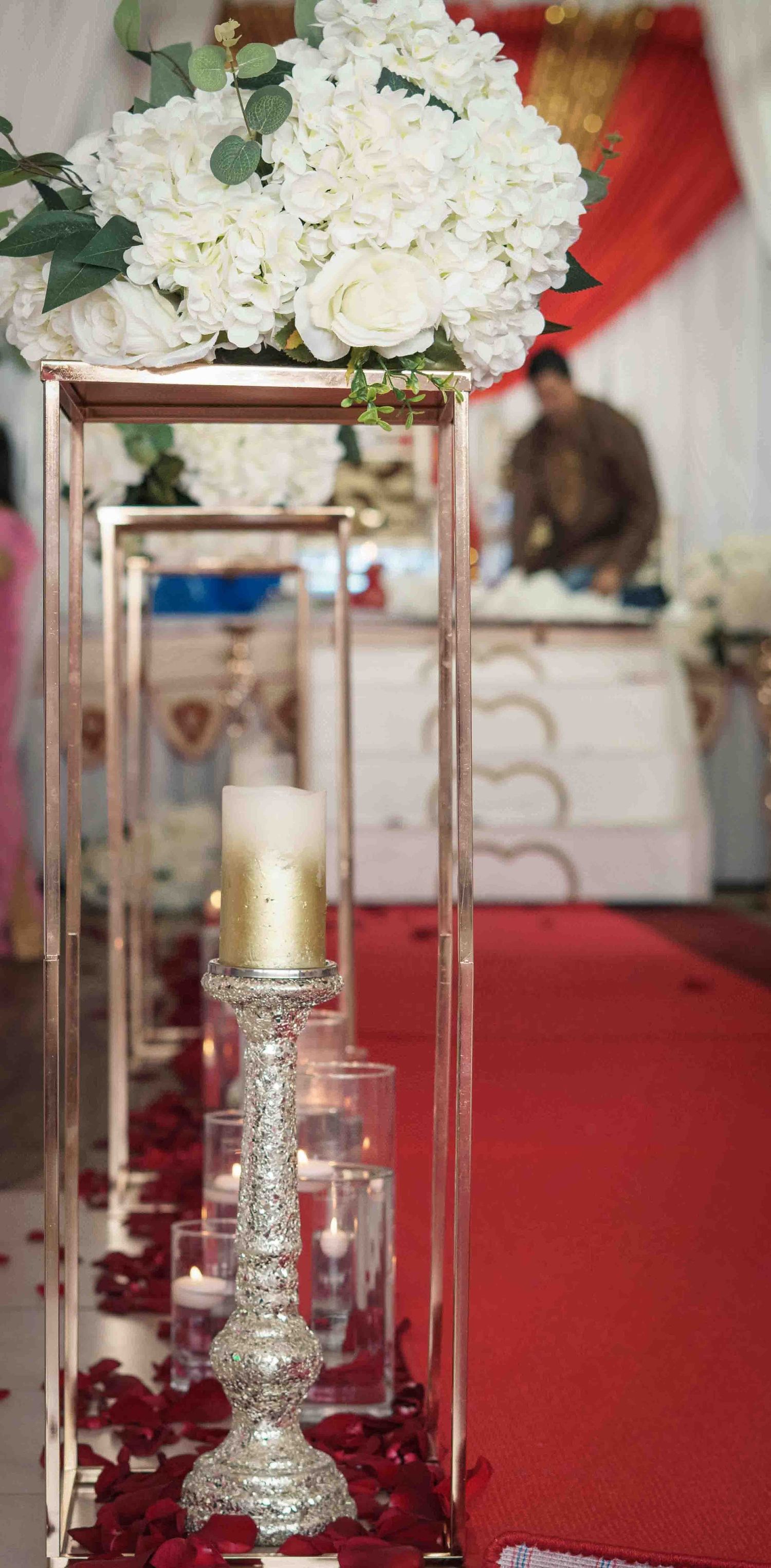 Elegant floral centerpiece with white roses and hydrangeas on crystal stands with candle accents.