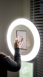 Series of interactive touchscreen displays mounted on a wall with window blinds visible.