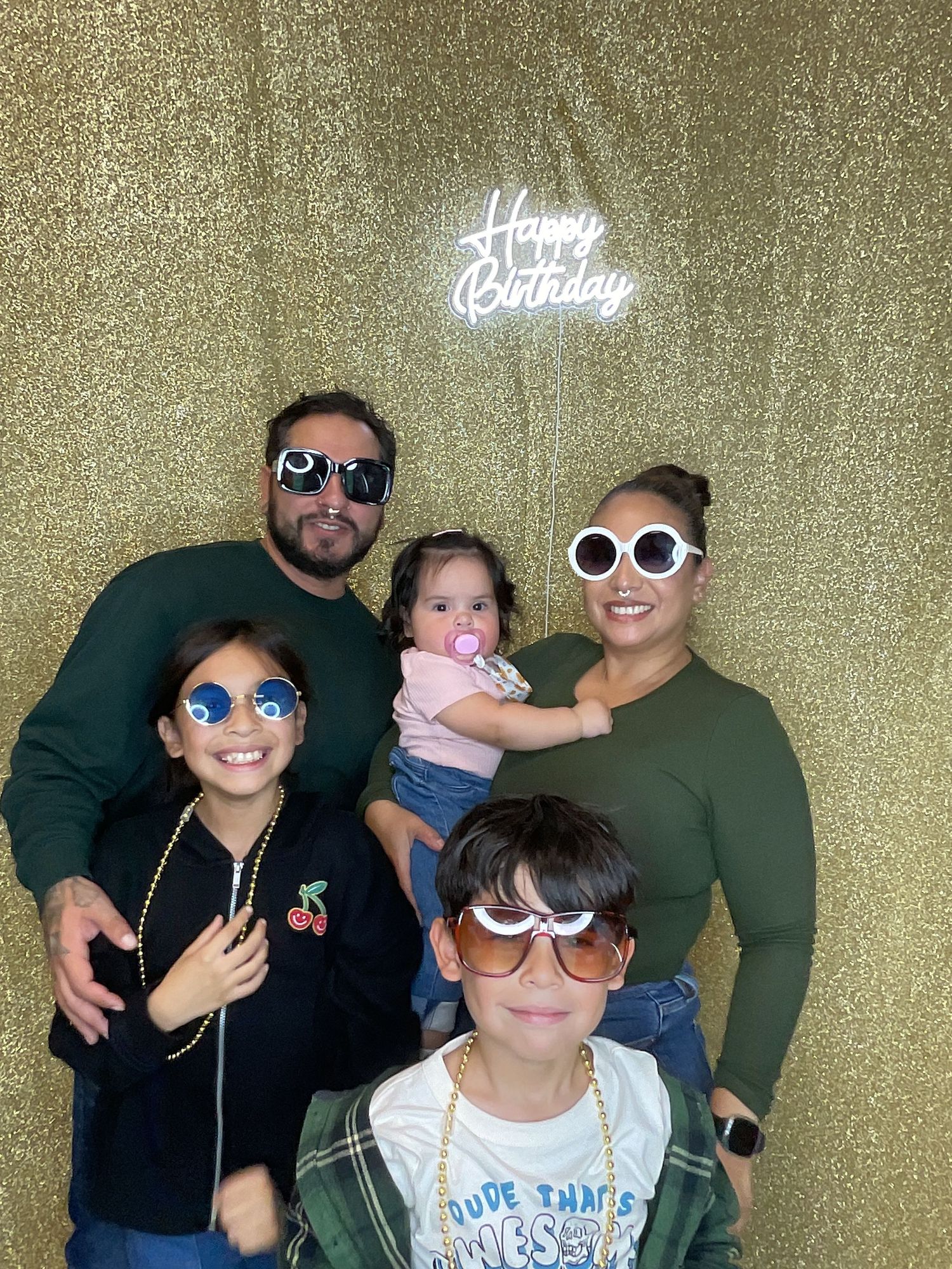 Party photos with people wearing fun sunglasses against a gold sparkly backdrop.