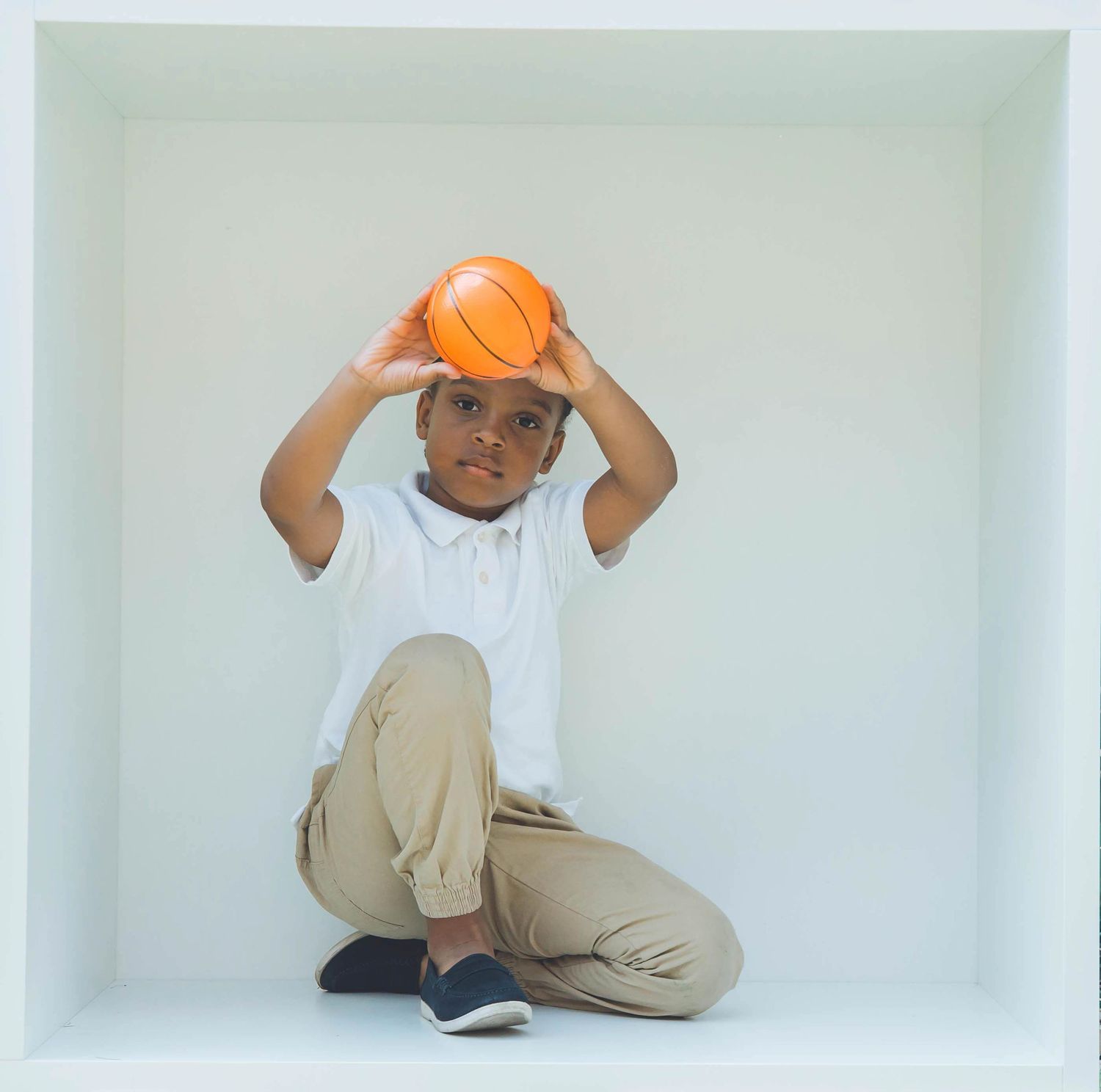 Child playing with a basketball in various poses against a white studio background.