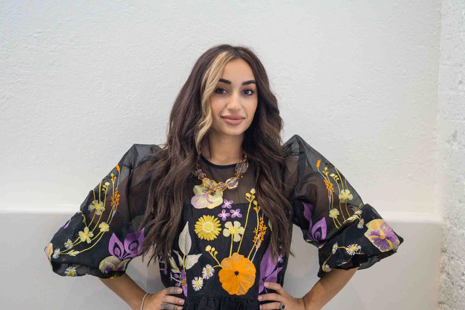 Dark floral dress with puff sleeves photographed in minimalist white studio space.