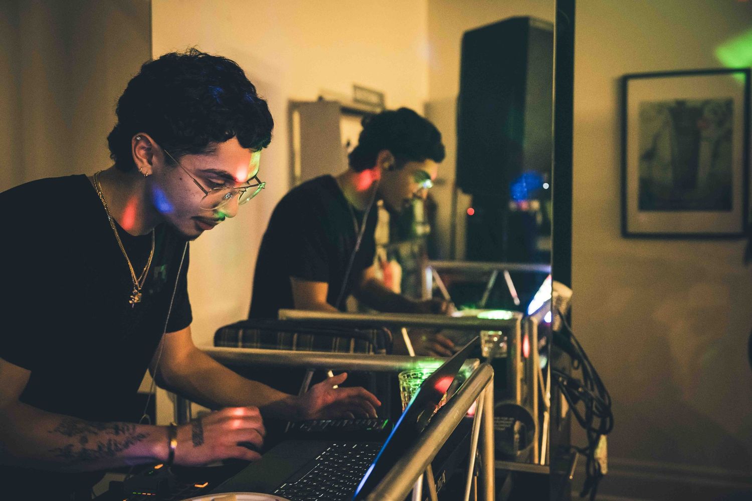 People using electronic devices in a dimly lit room with ambient lighting.