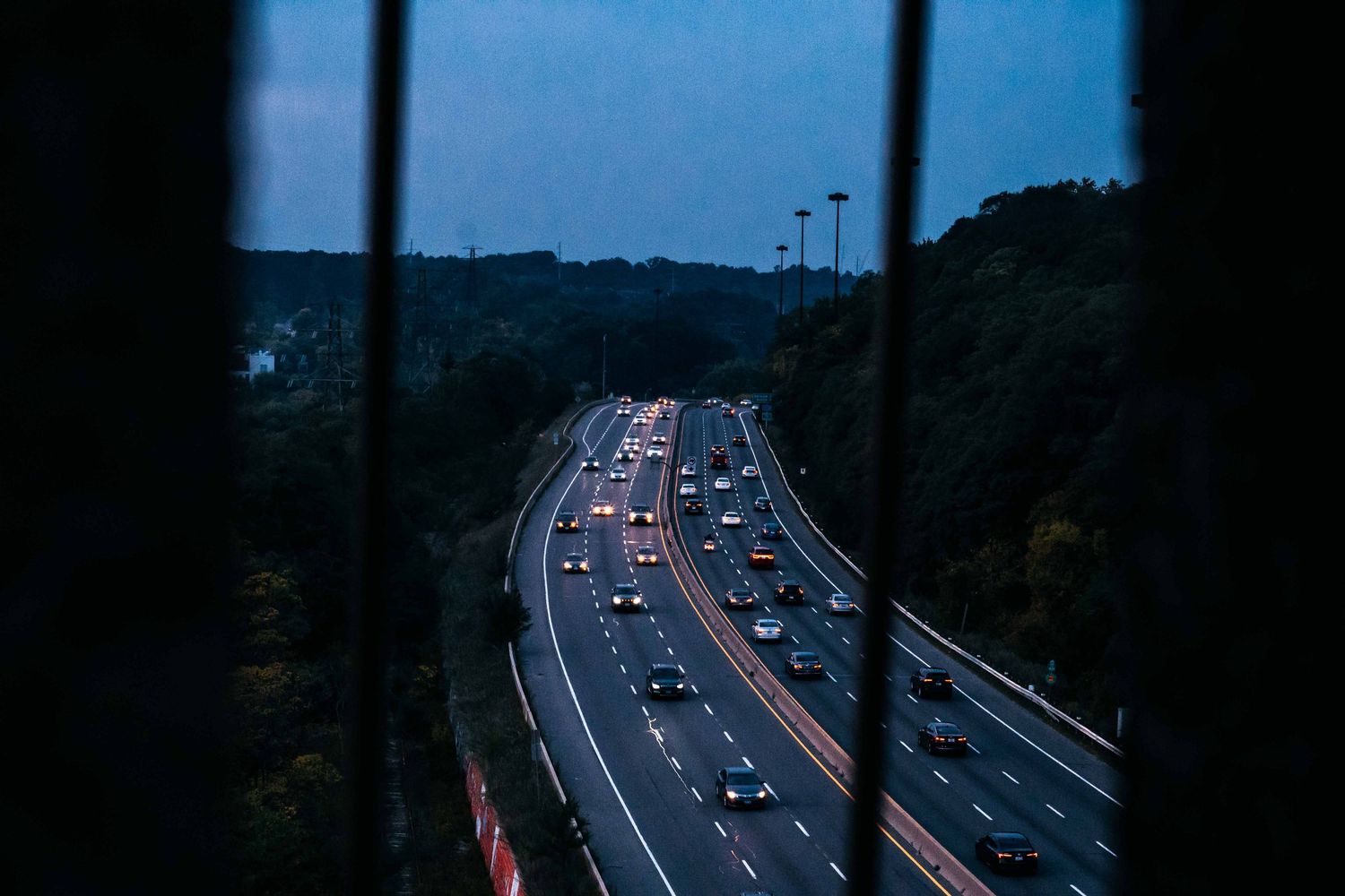 Highway traffic at dusk with car headlights and taillights creating light trails on a curved road.