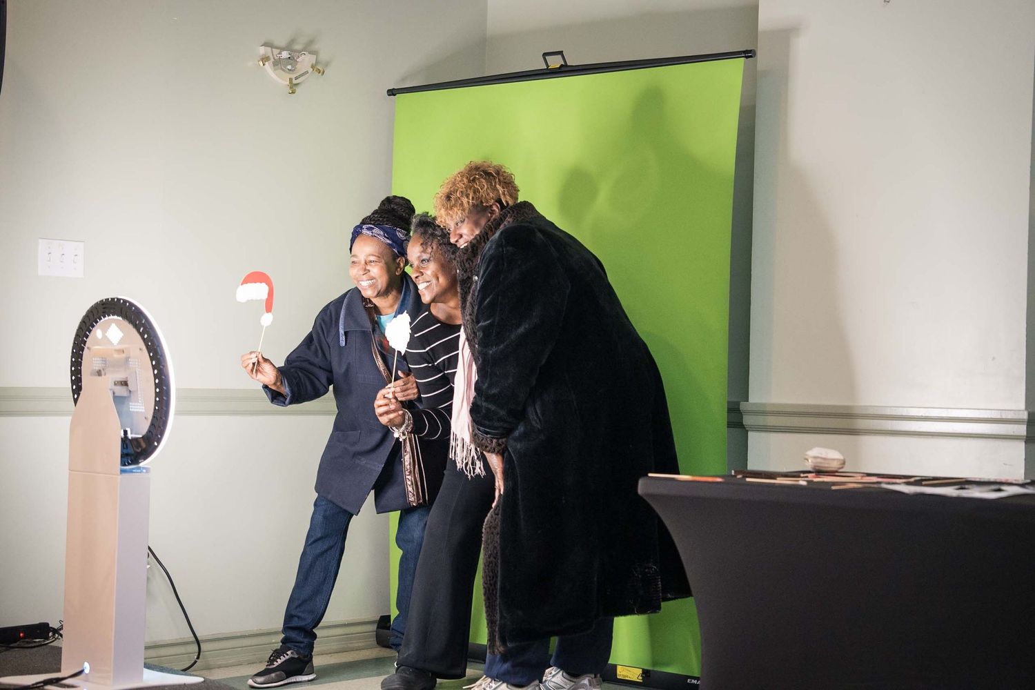 Behind the scenes view of photo shoot setup with green wall and lighting equipment.