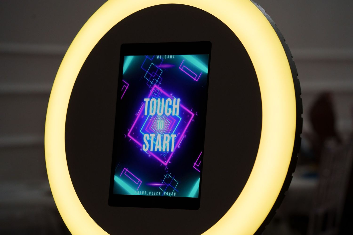 Neon 'Touch to Start' interface display illuminated by a ring light.