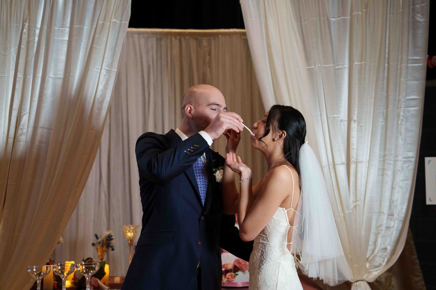 A romantic wedding reception scene with couples dancing in an elegant ballroom with white curtains.