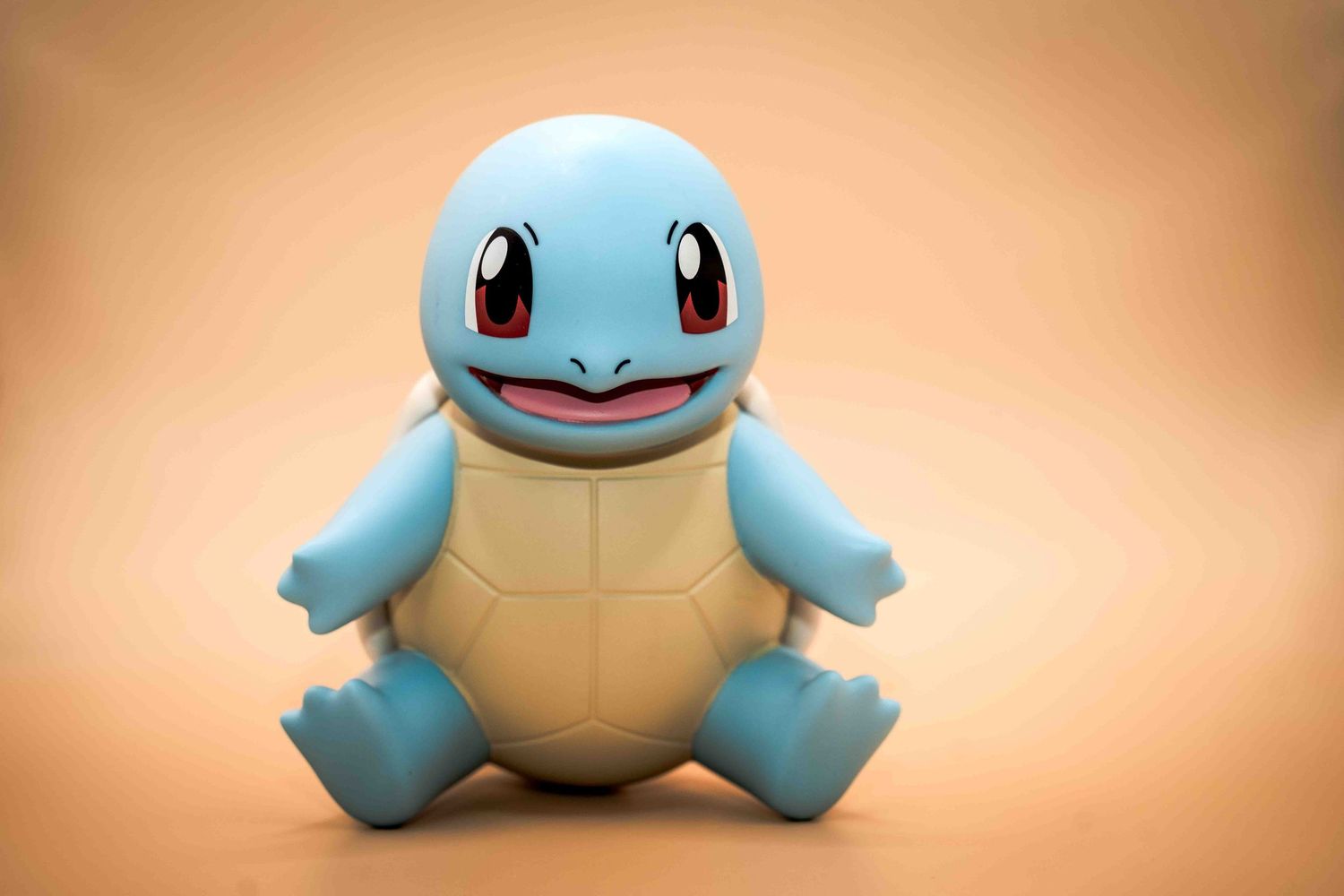 Squirtle Pokemon figure sitting on a beige background, smiling.