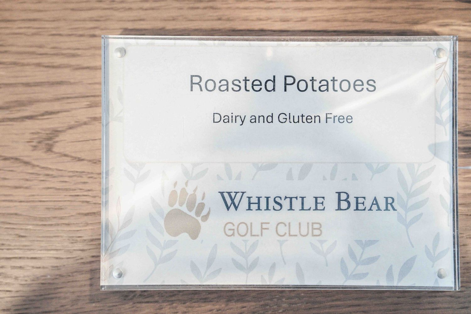 Whistle Bear Golf Club sign displaying Roasted Potatoes menu item labeled dairy and gluten free.