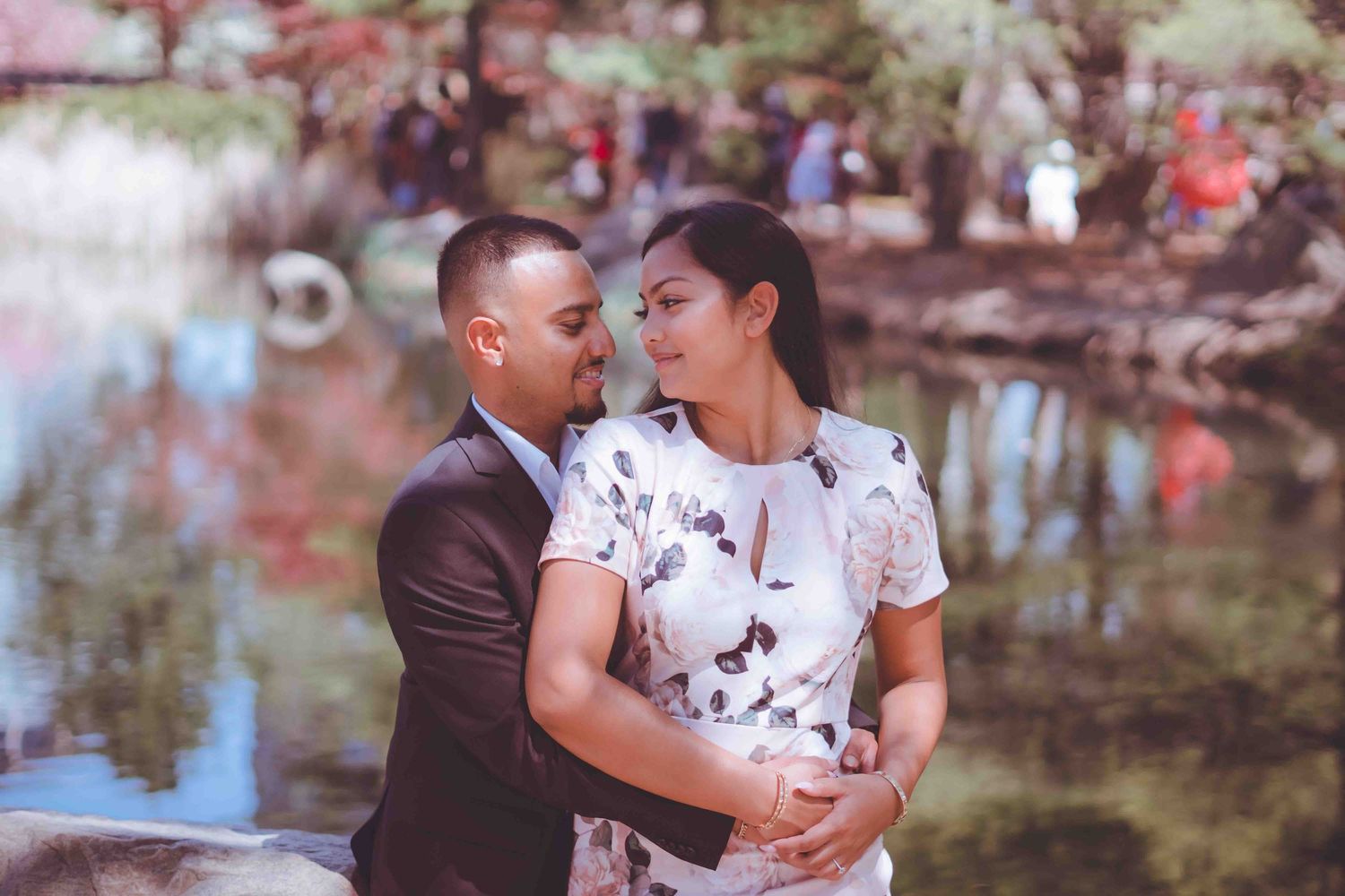 Romantic engagement photos captured among blooming cherry blossom trees in a park setting.