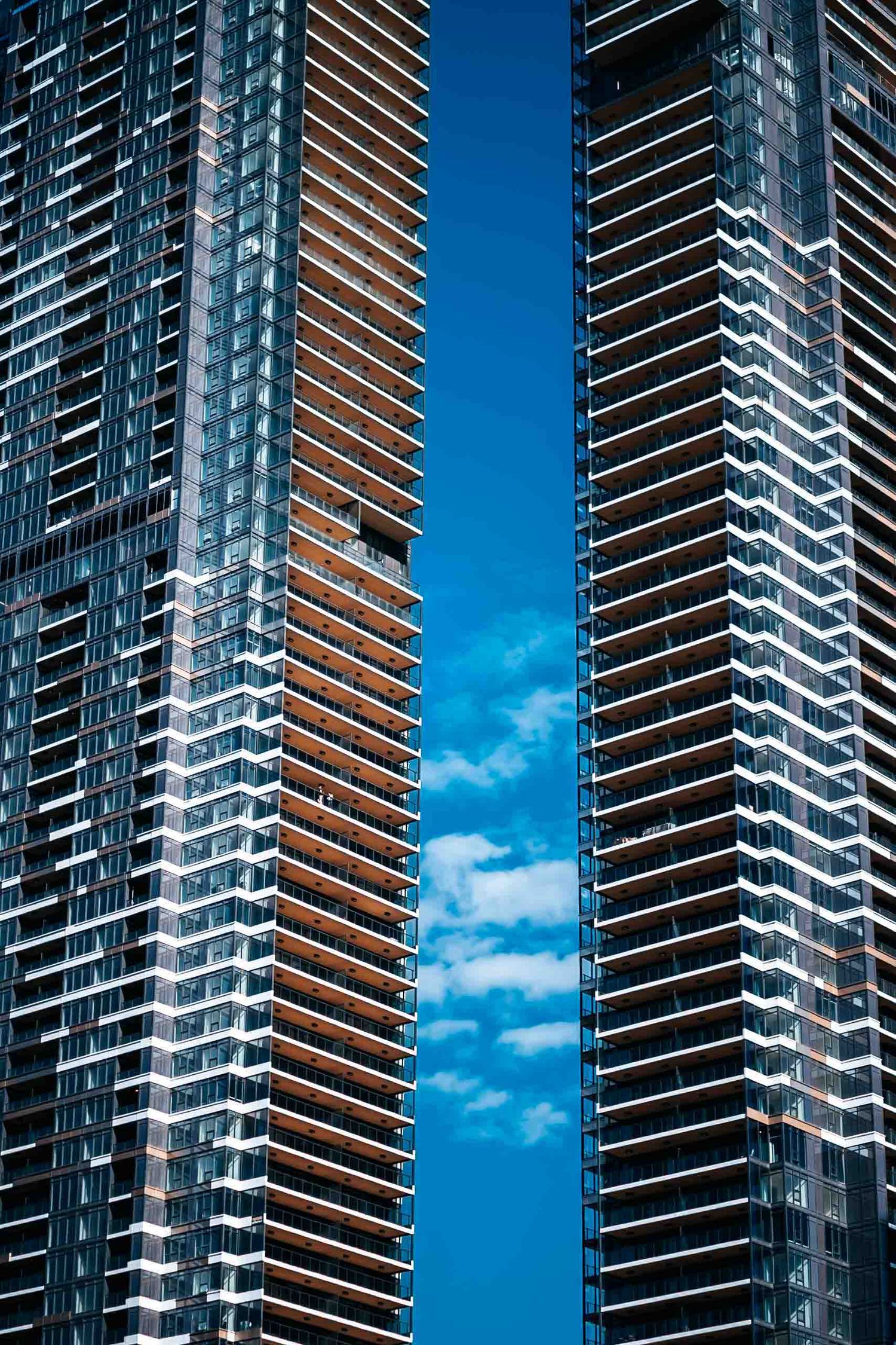 Contemporary residential tower facades with geometric balconies against blue sky.