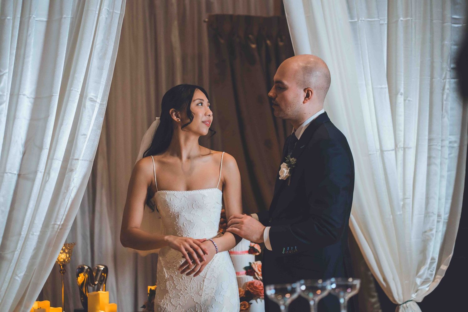 A couple shares an intimate moment during their wedding reception surrounded by white curtains and decor.