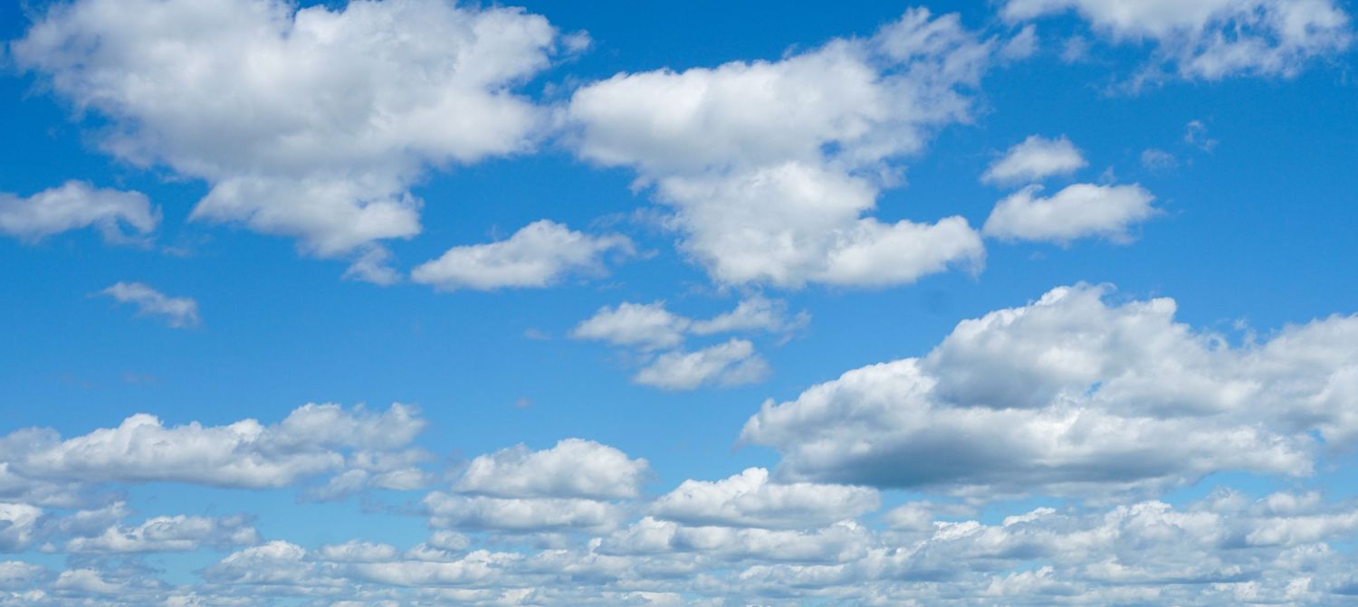 Panoramic view of white puffy clouds against vibrant blue sky on sunny day.
