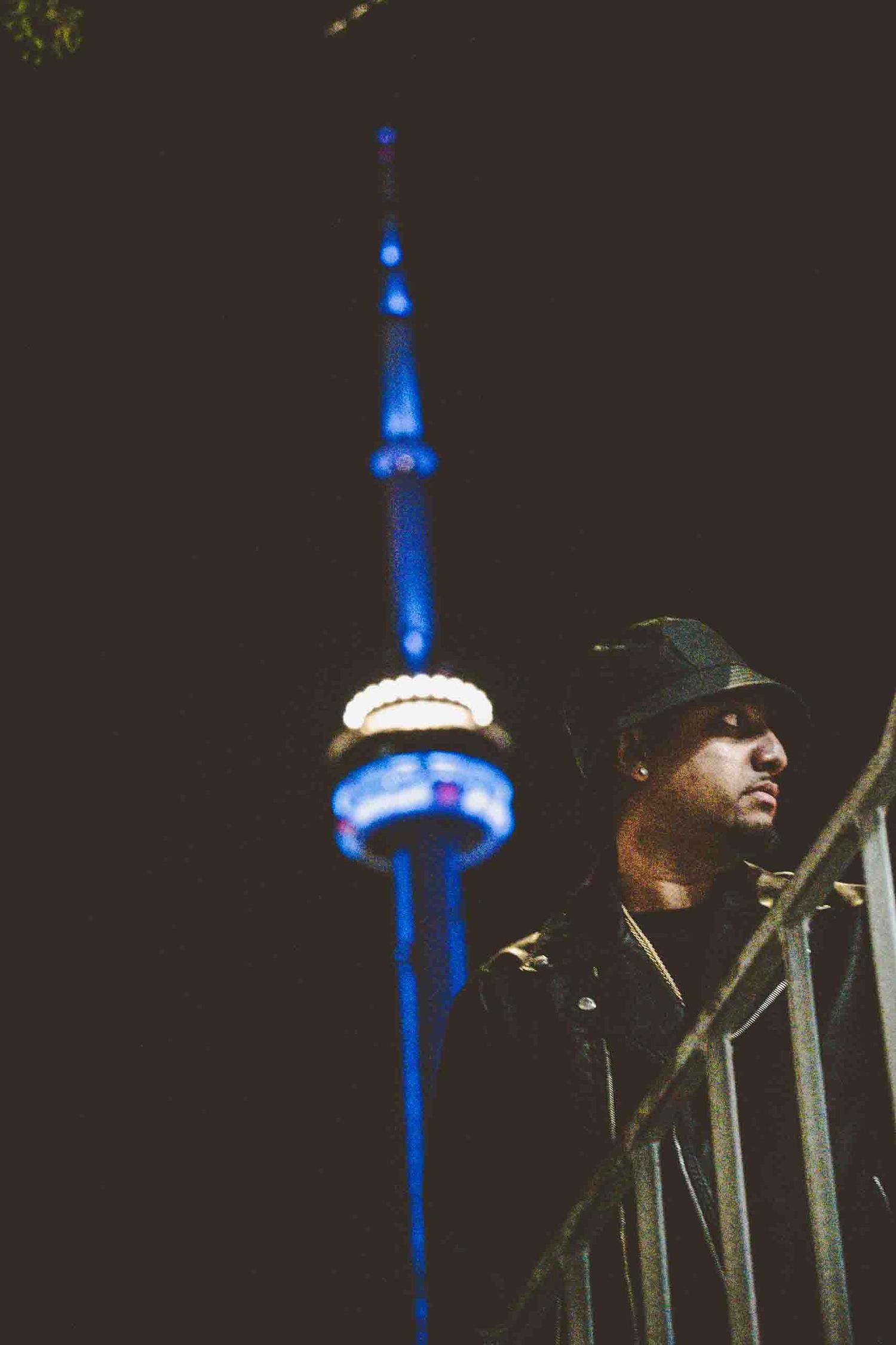 Night cityscape with illuminated CN Tower in Toronto against dark sky.