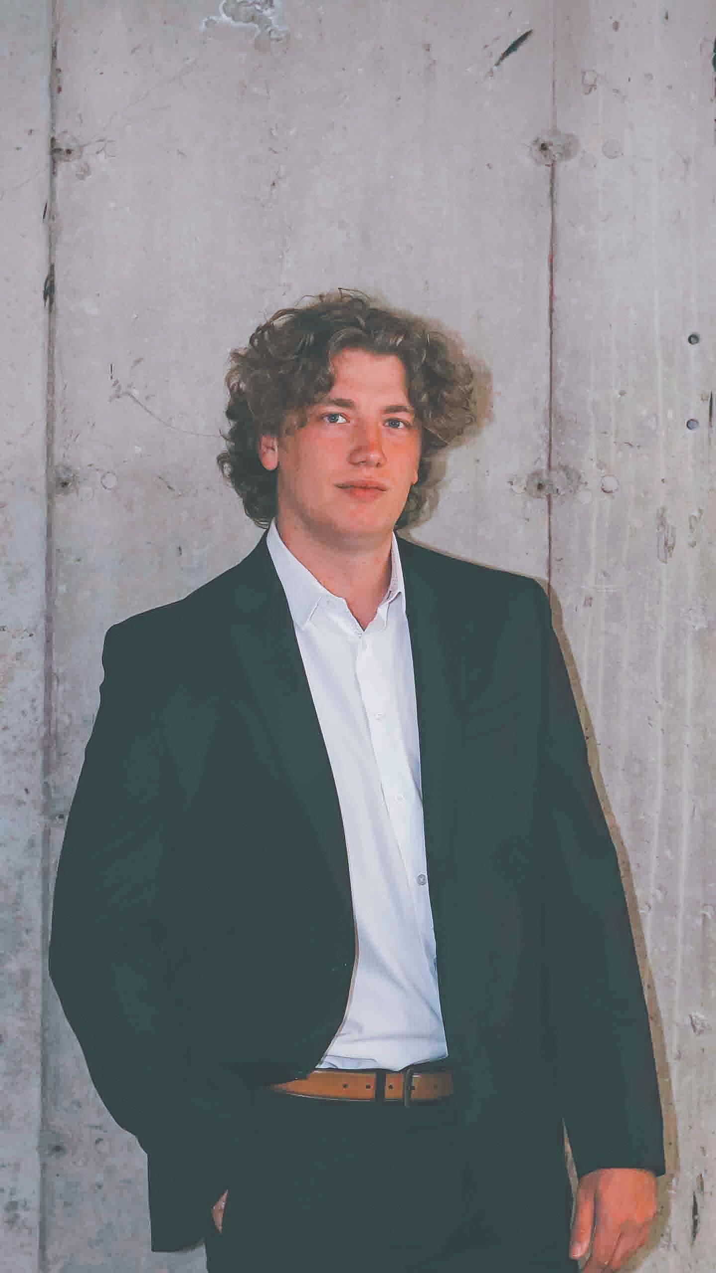 Stylish business portraits in dark suits against light industrial wall.