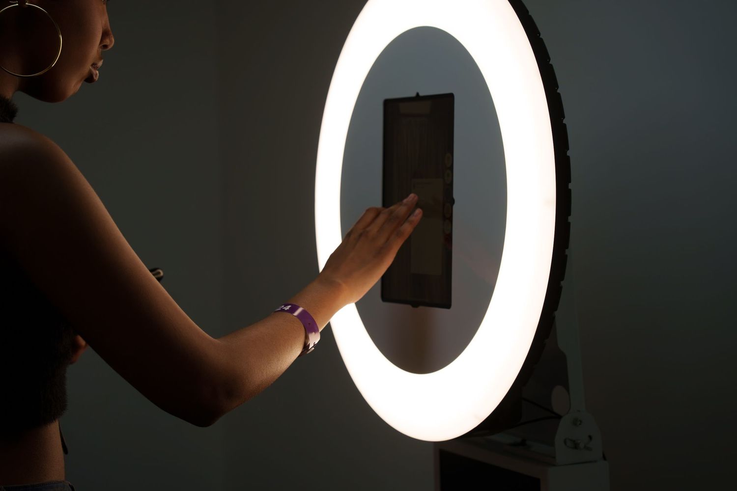 Silhouetted hands interacting with device against bright circular light.