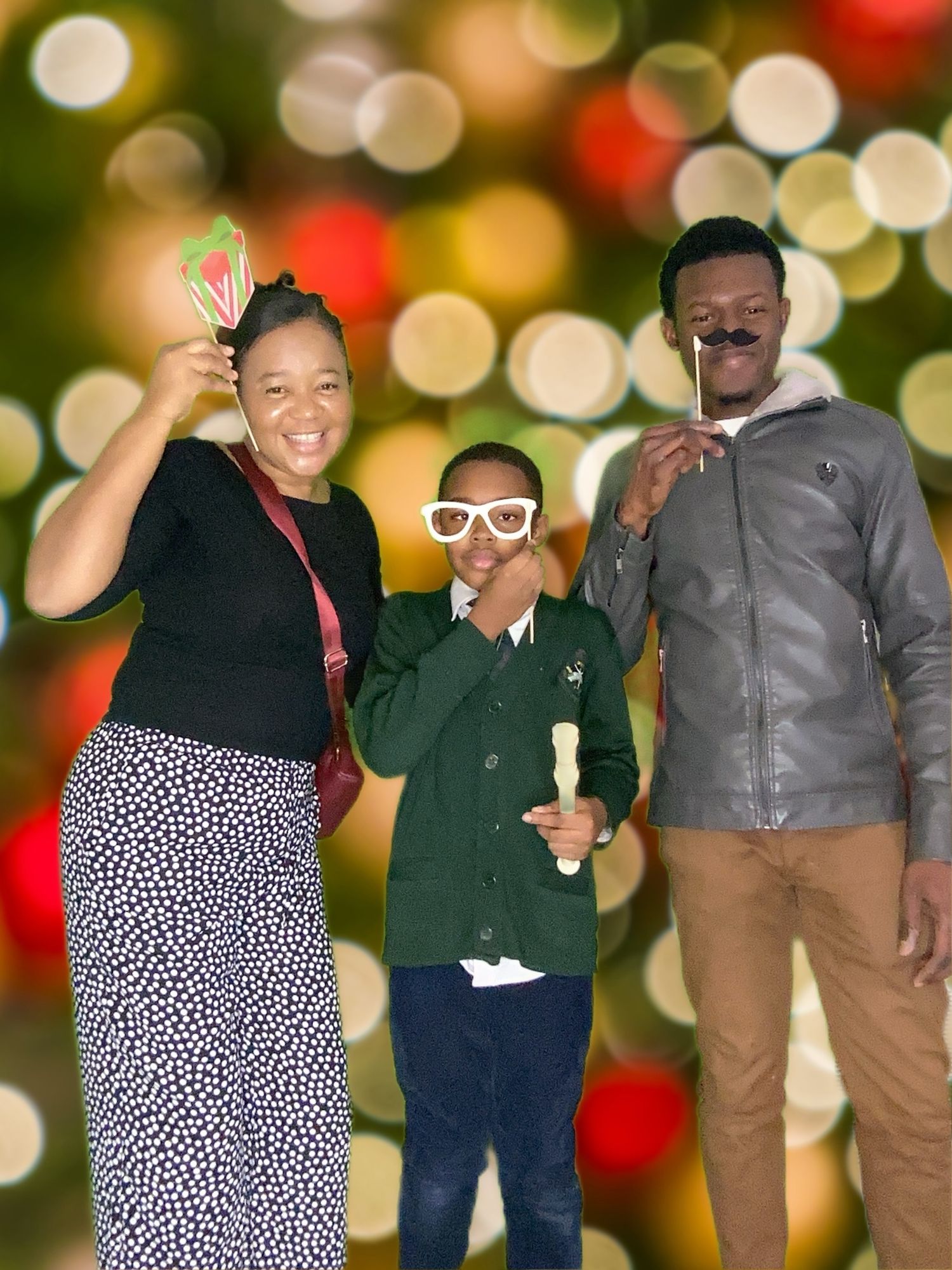 Family poses with props against festive holiday bokeh background.