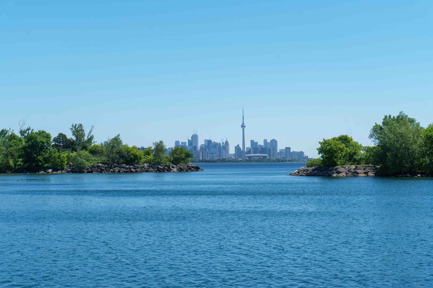 Panoramic view of Toronto's waterfront skyline with CN Tower visible across the harbor.