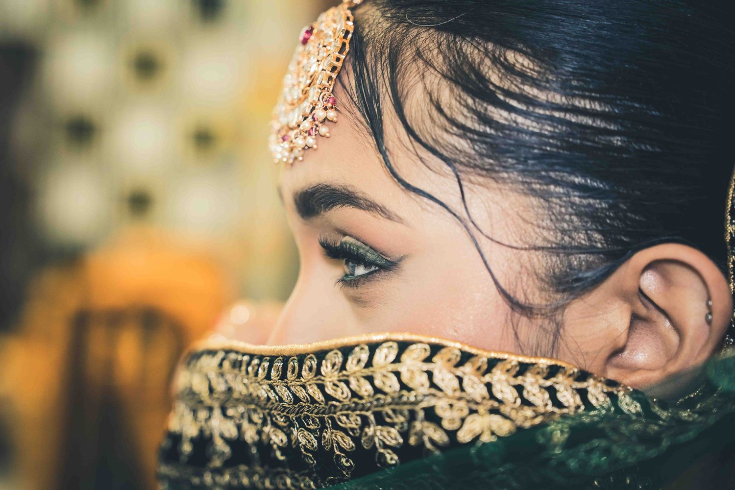 A close-up detail shot of an ornate gold embroidered pattern on dark fabric with delicate stitching and beadwork.