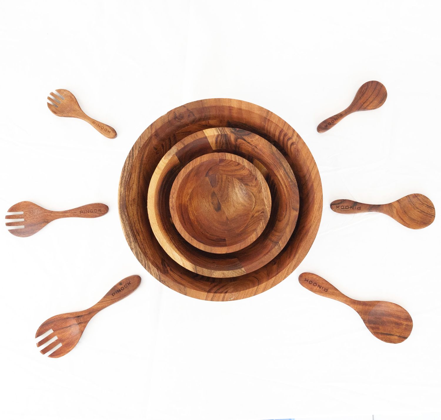 PINOOK acacia wood nesting salad bowl set with four bowls and six serving utensils arranged in flat lay display.