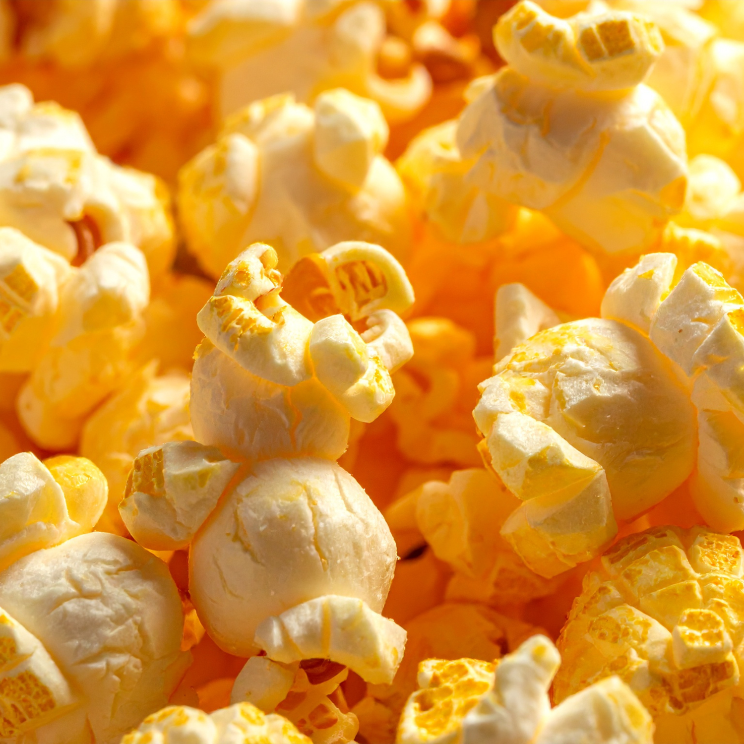 Close-up macro shot of freshly popped buttery popcorn kernels showing golden texture and detail.